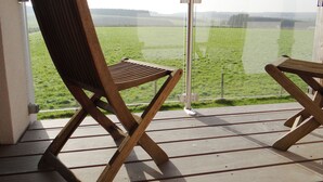 Una silla de madera en un balcón con vistas a un campo verde.