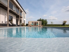 Relax by the serene pool, surrounded by a contemporary building with expansive views.