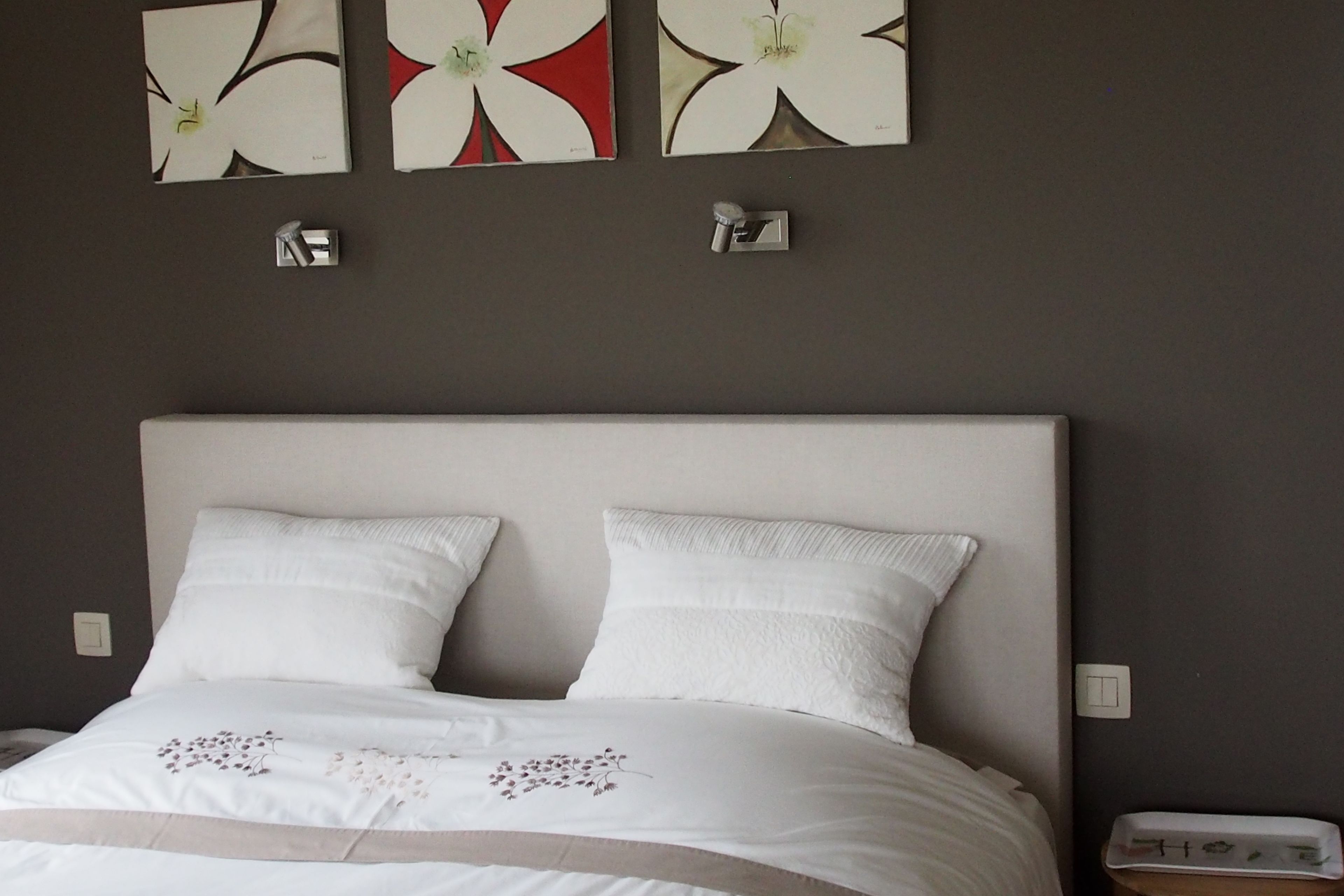 Ein Schlafzimmer mit einem großen Bett, weißer Bettwäsche und drei Wandleuchten.