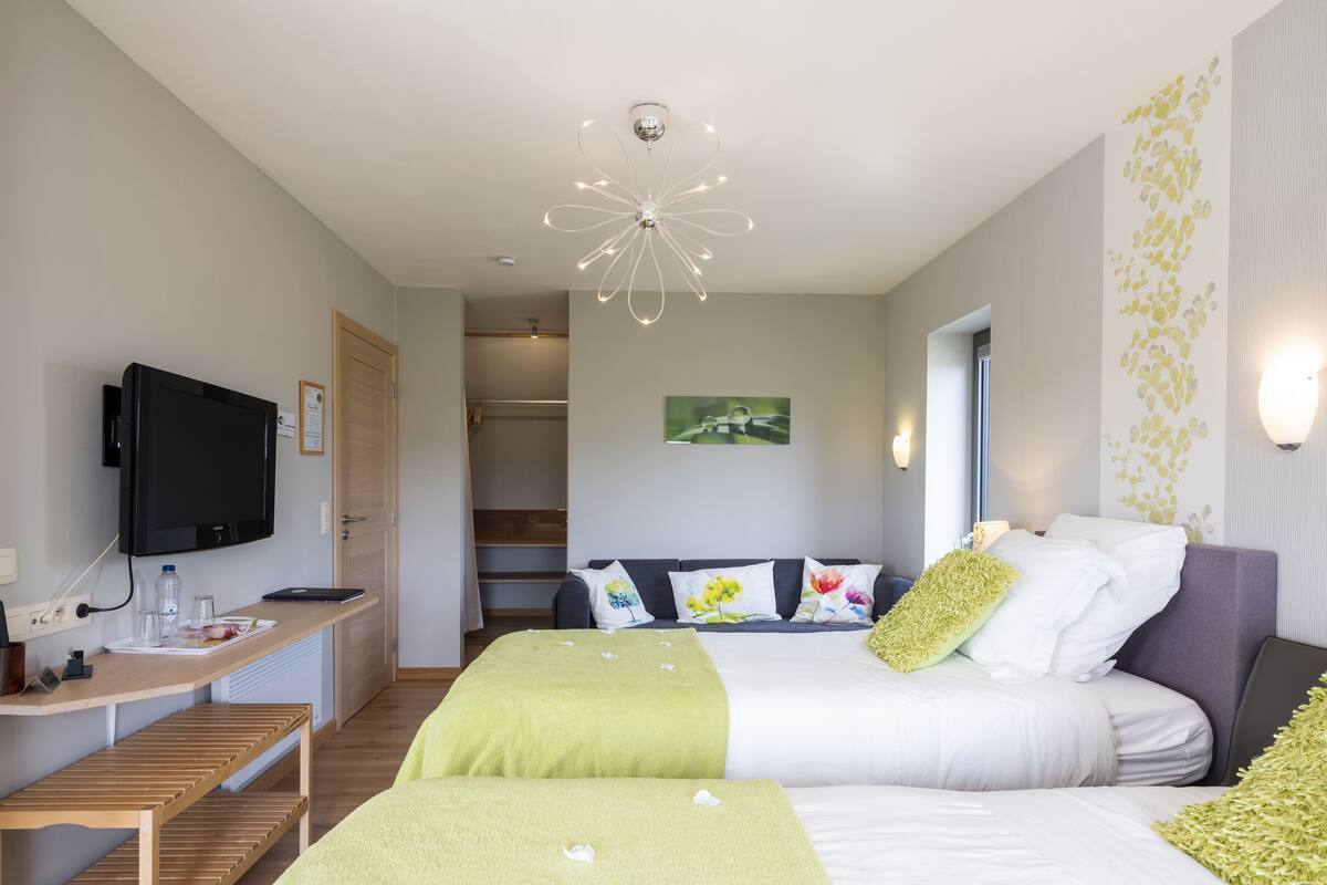 Een moderne hotelkamer met een bed, een bureau, een televisie en een douchehoek.