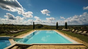 A rectangular swimming pool with a tiled edge, surrounded by lounge chairs and a grassy area. - Agriturismo Corte in Poggio (Cerreto Guidi)