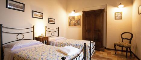 Une chambre avec deux lits simples, une porte en bois et une chaise.