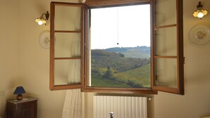 A room with a large window offering a view of a green landscape. - Agriturismo Corte in Poggio (Cerreto Guidi)