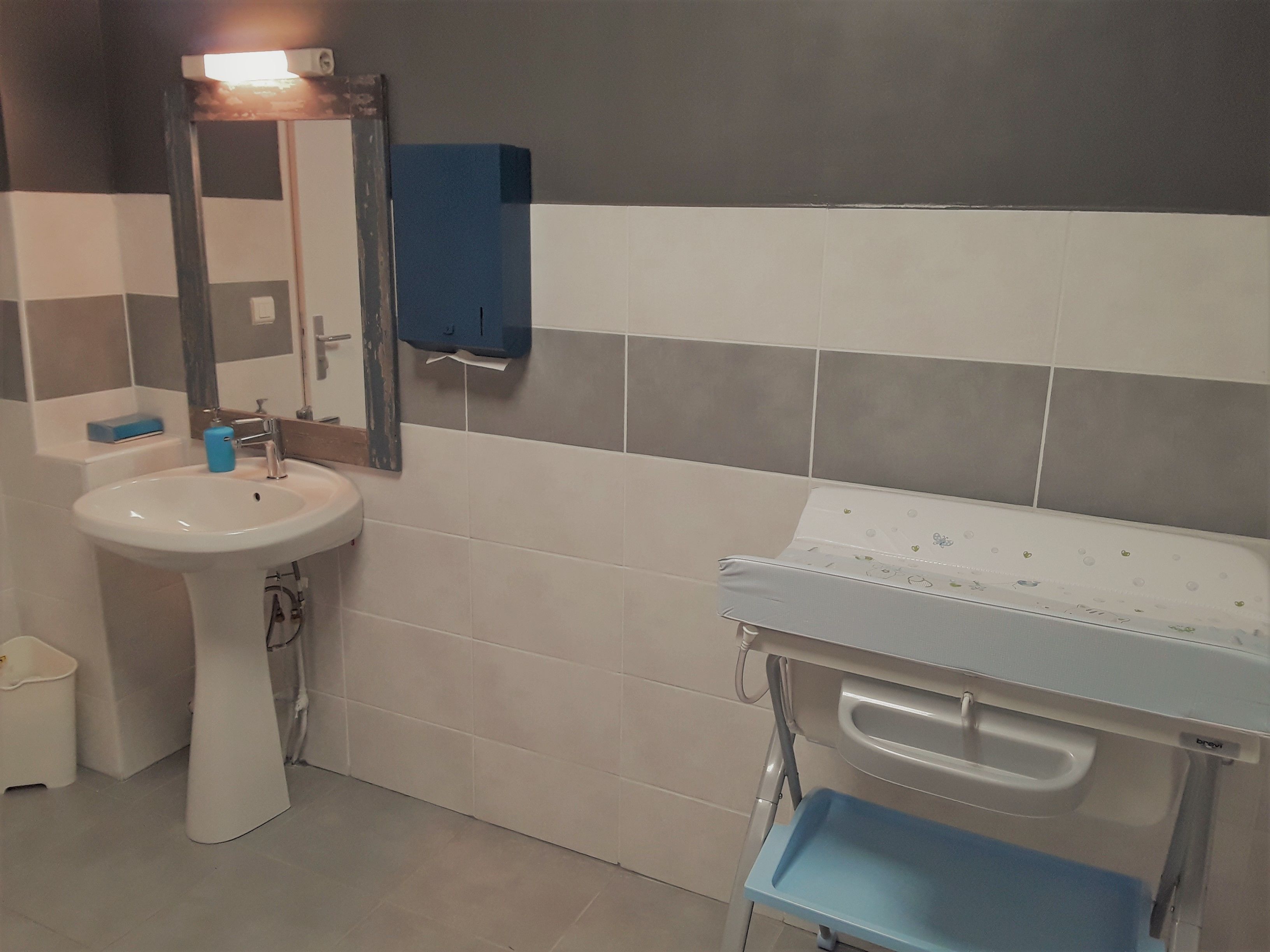 A bathroom with a white sink, a mirror, and a blue towel hanging on the wall.