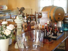 Un espace bar avec un assortiment de bouteilles, une grande barrique en bois et une statue d’ange.
