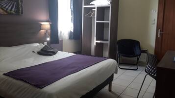 Une chambre d’hôtel avec un lit, une chaise, une armoire et un tableau au mur.