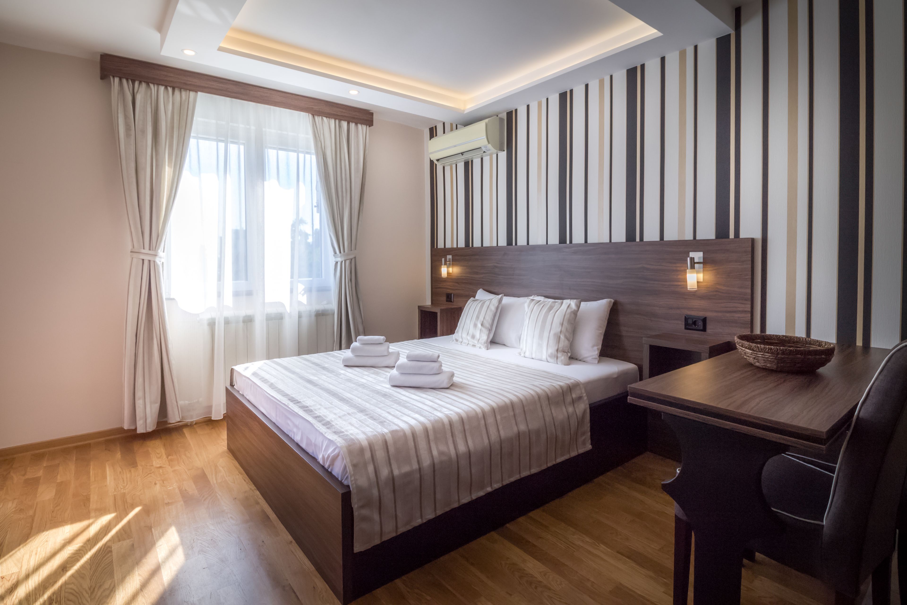 Ein modernes Hotelzimmer mit einem großen Bett, einem Holztisch und einer gestreiften Wand.