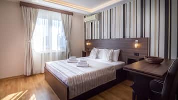 Una moderna camera d'albergo con un letto grande, una scrivania in legno e una parete a righe.