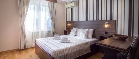 Ein modernes Hotelzimmer mit einem großen Bett, einem Holztisch und einer gestreiften Wand.