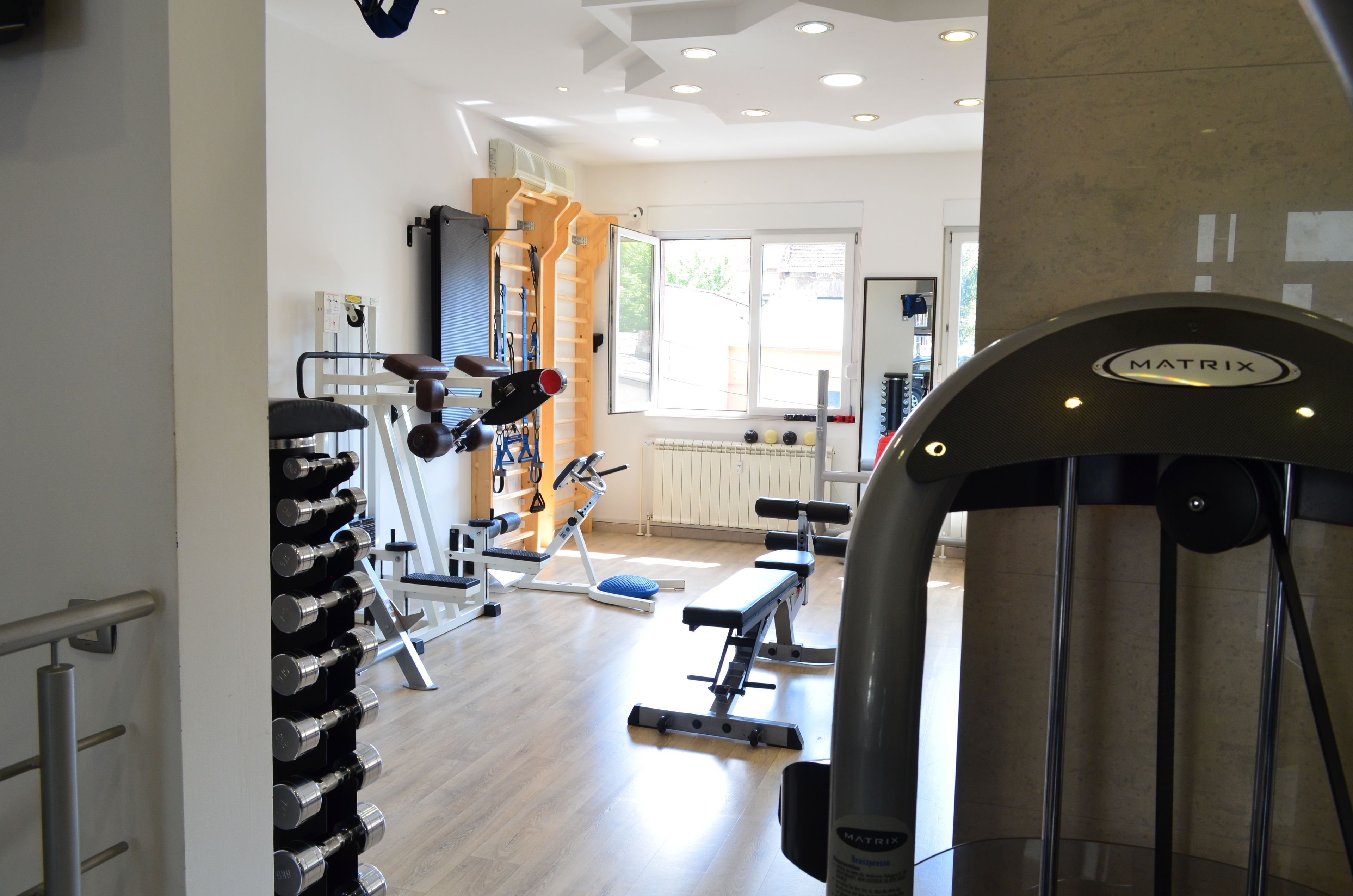 A gym with various exercise equipment, including dumbbells, benches, and a treadmill.