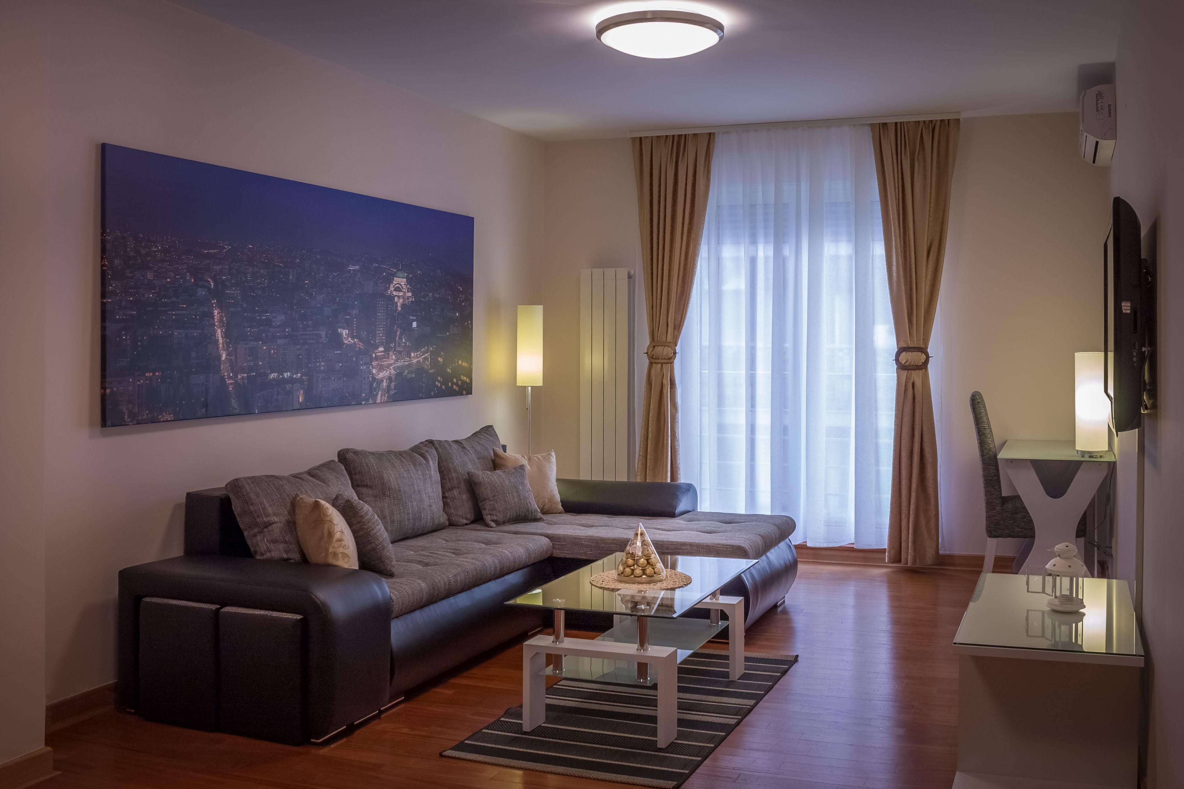 Una sala de estar moderna con un sofá, una mesa de centro y un cuadro de un paisaje urbano en la pared.