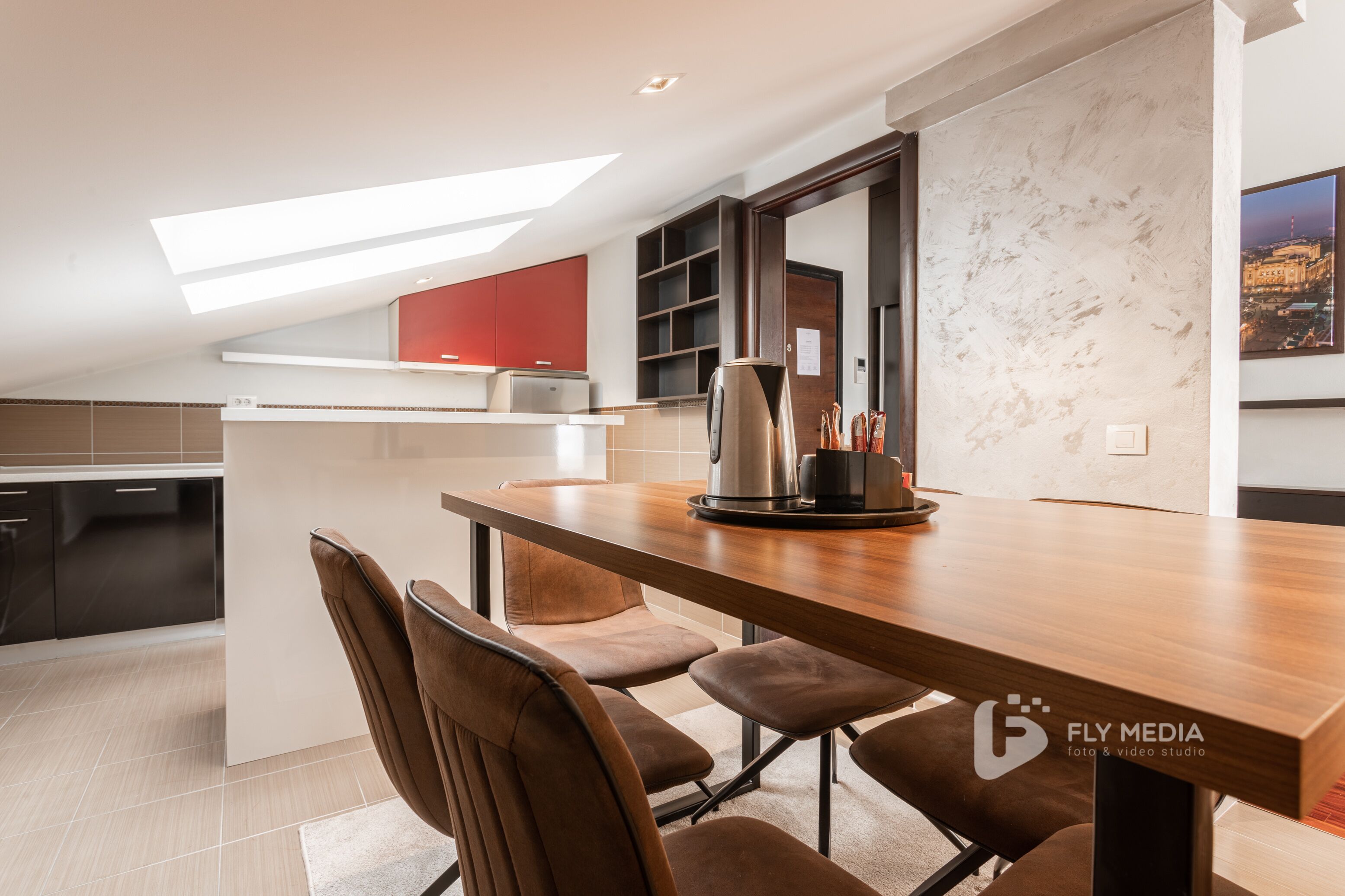 A modern kitchen with a wooden dining table, brown chairs, and a built-in oven.