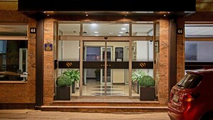 Entrada de hotel con puerta de vidrio, plantas en macetas y un letrero que indica el piso 44.