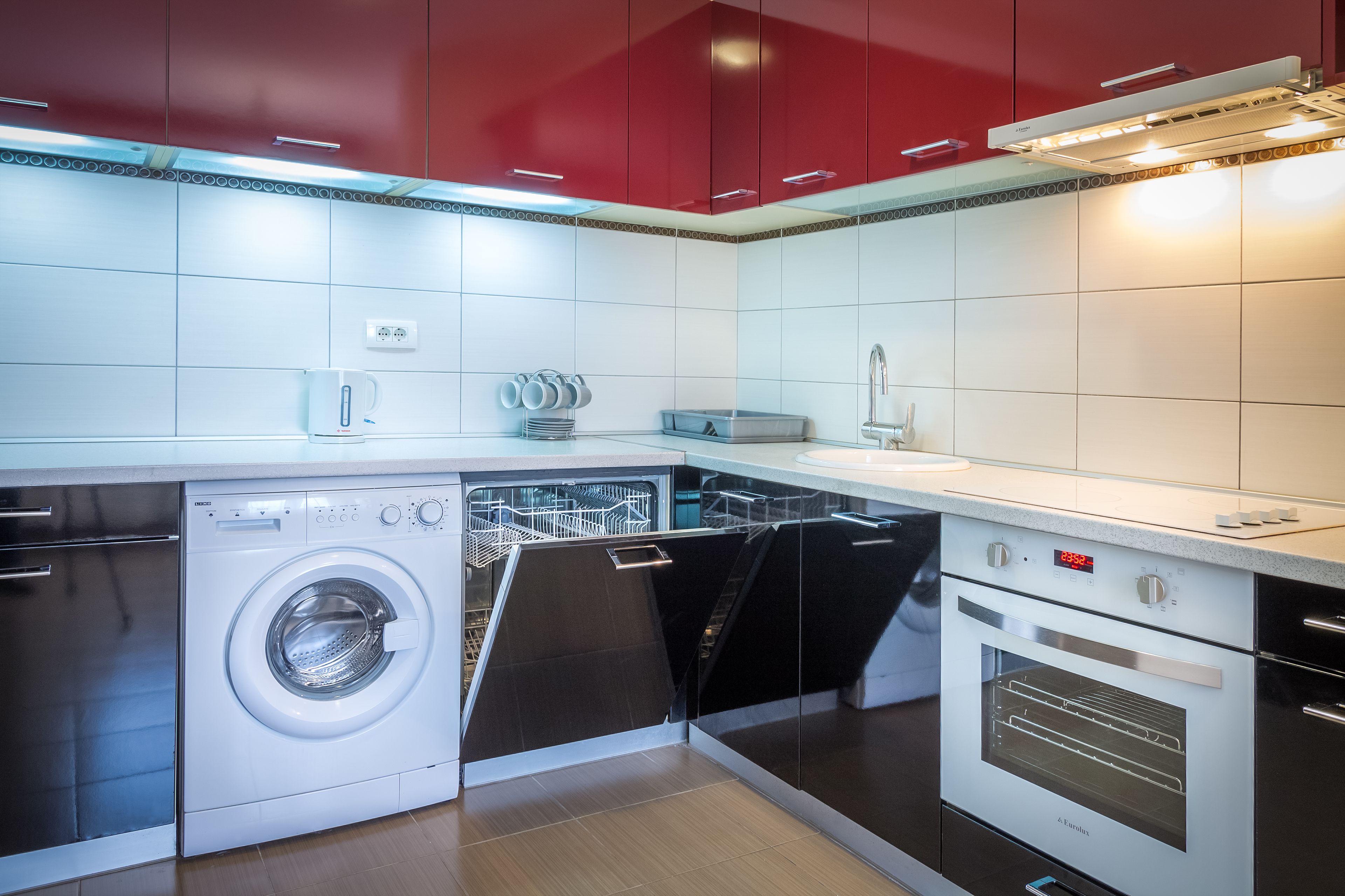 A modern kitchen with a built-in dishwasher, oven, and a coffee machine.