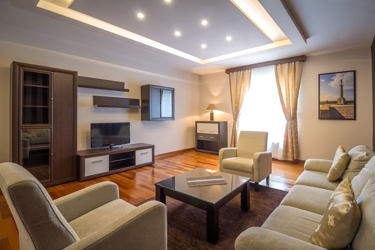 A modern living room with a sofa set, a glass coffee table, a TV, and a lamp.