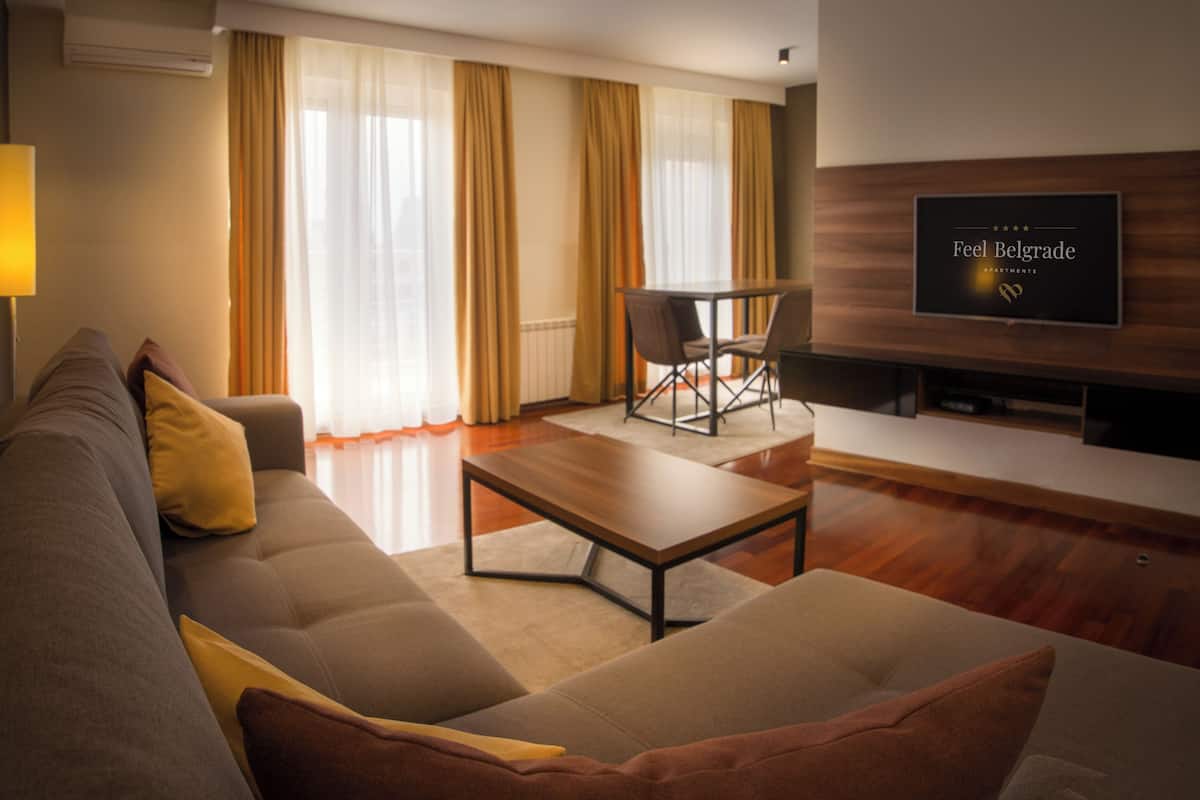 A modern living room with a sofa, coffee table, and a flat-screen TV mounted on the wall.