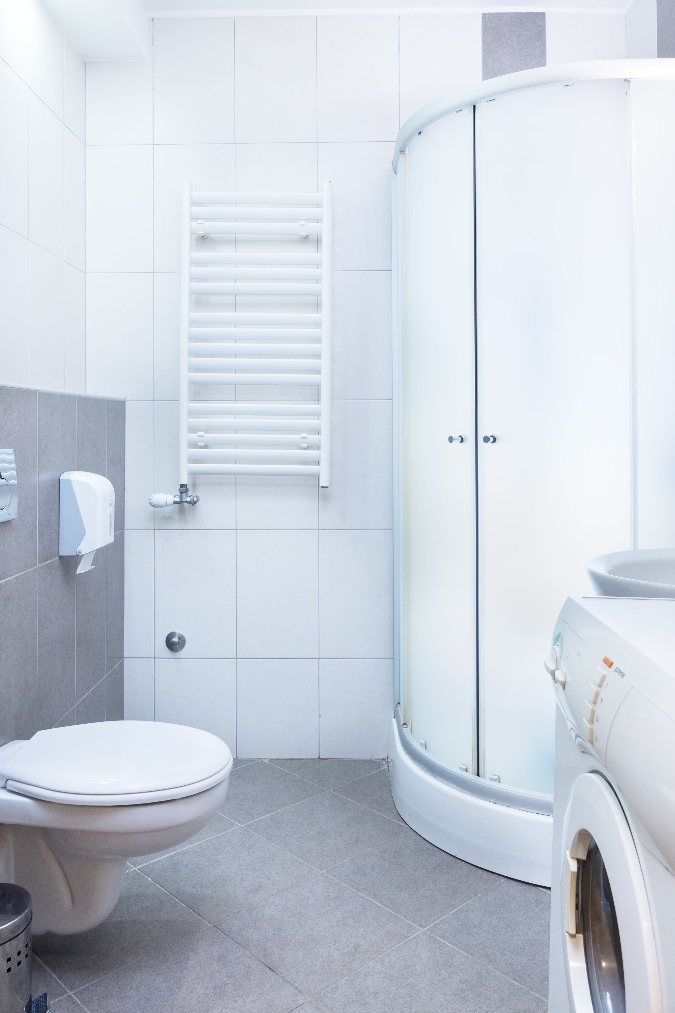 A modern bathroom with a toilet, a washing machine, and a shower enclosure.
