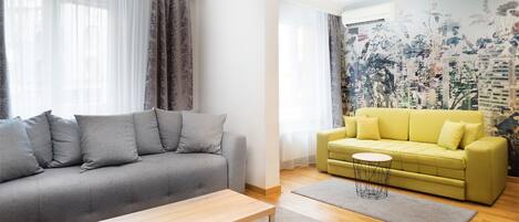 A living room with a grey sofa, a yellow sofa, a wooden coffee table, and a cityscape mural on the wall.