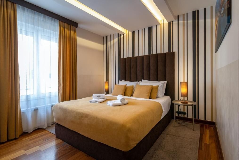 Ein Hotelzimmer mit einem großen Bett, einem Nachttisch mit Lampe und einem gestreiften Wanddesign.