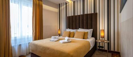 Ein Hotelzimmer mit einem großen Bett, einem Nachttisch mit Lampe und einem gestreiften Wanddesign.