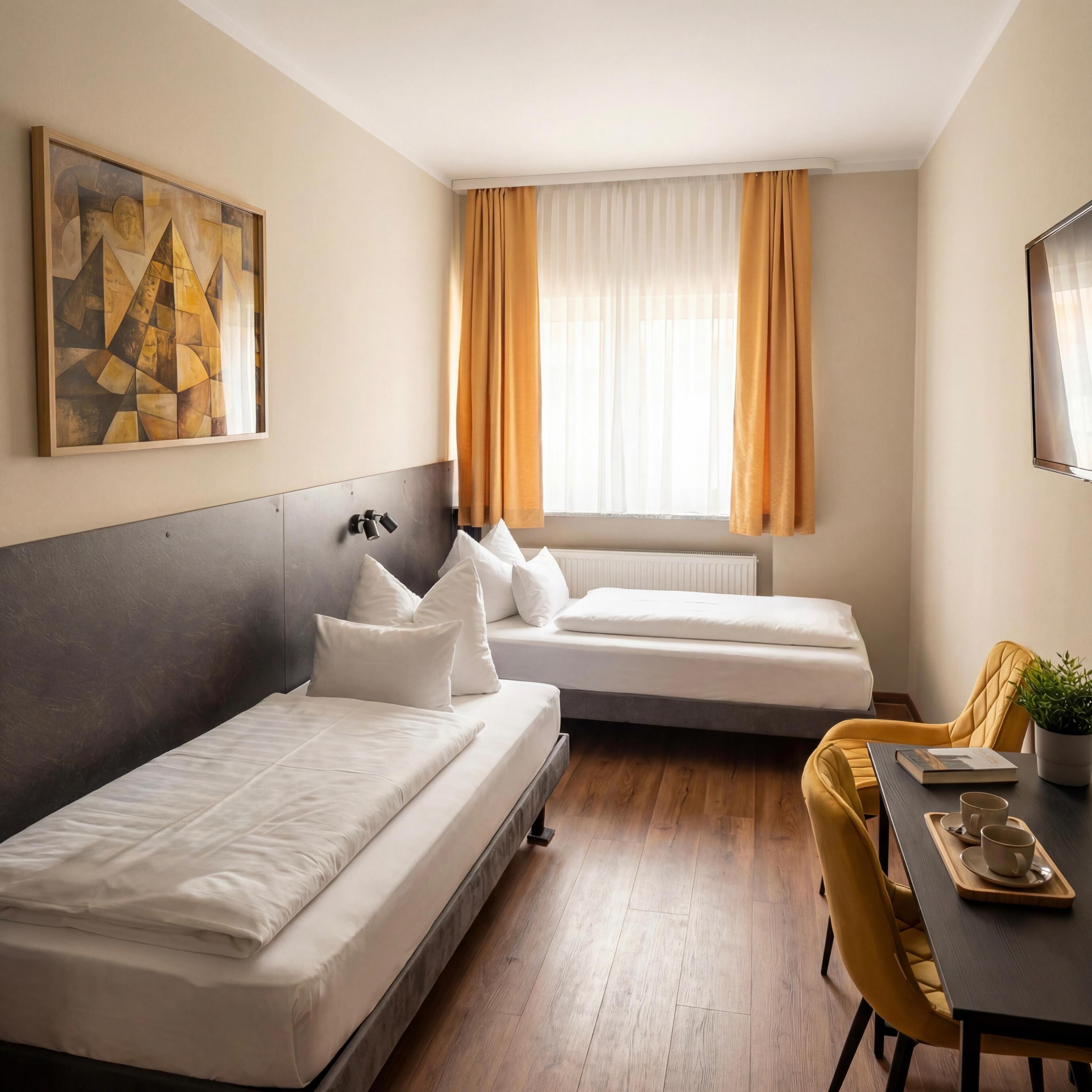 Een hotelkamer met twee bedden, een bureau met stoel, een plant in pot en een raam met gordijnen.