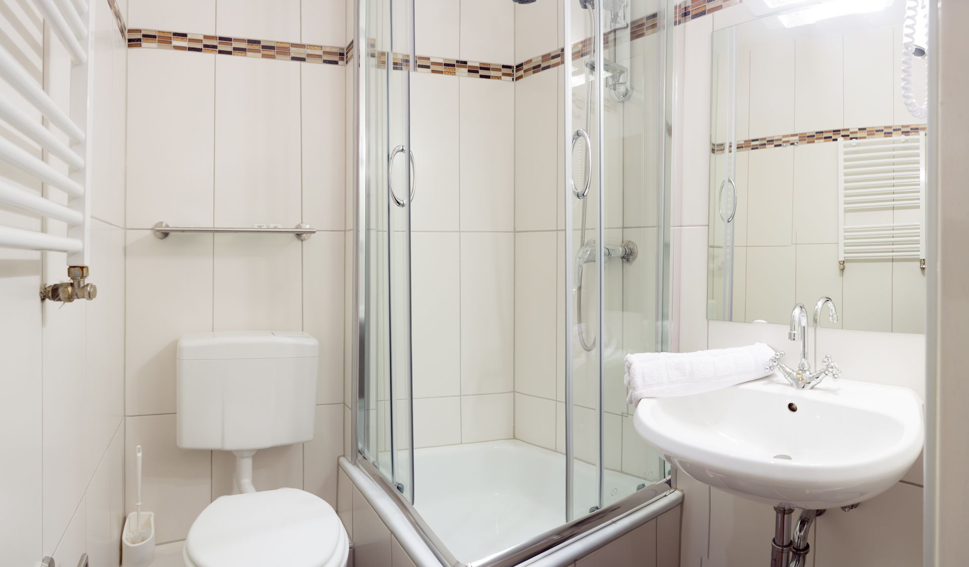 Une salle de bain moderne avec une douche à parois de verre, des toilettes blanches et un lavabo avec une serviette.