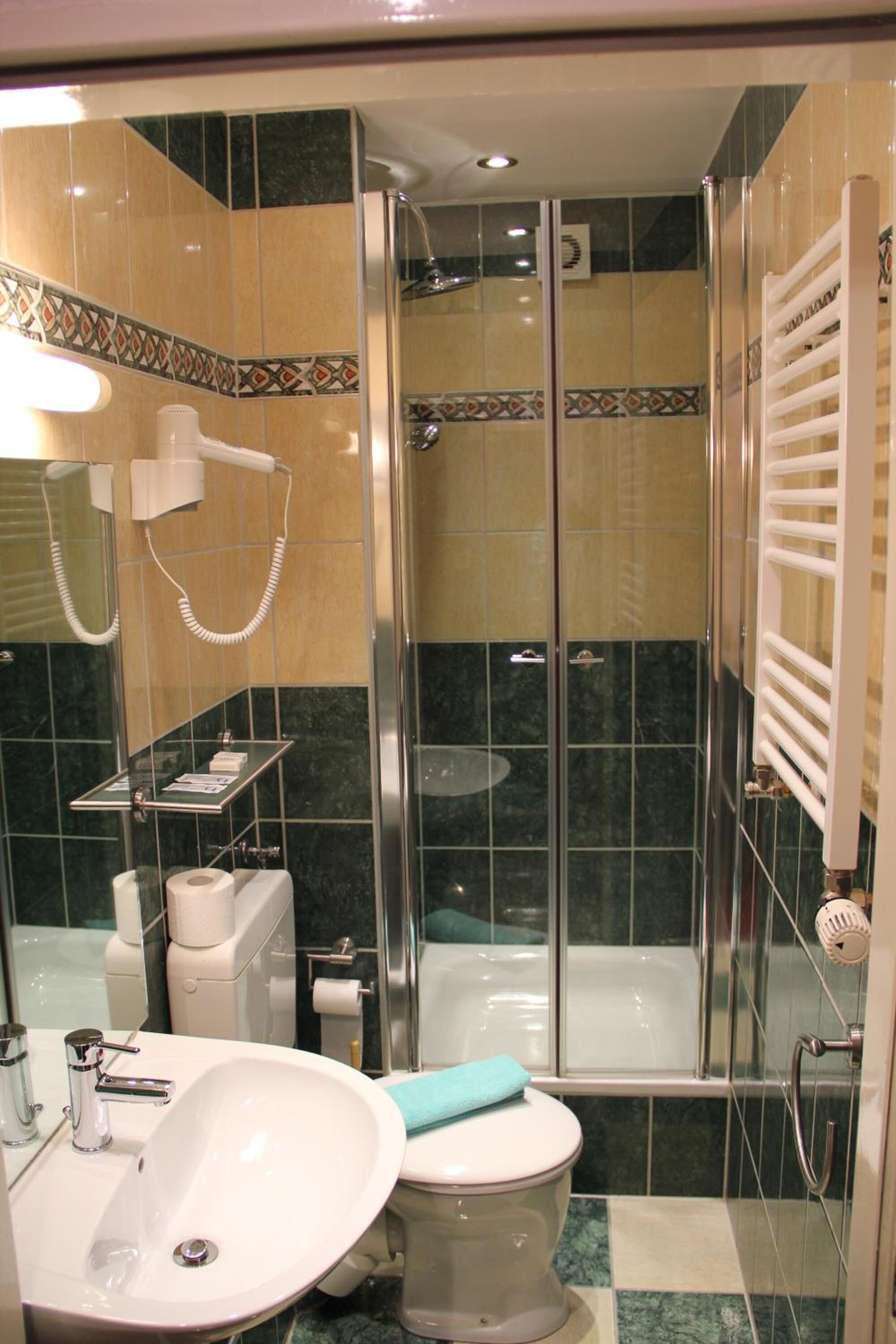 Ein Badezimmer mit Dusche, Toilette, Waschbecken und Handtuchhalter.