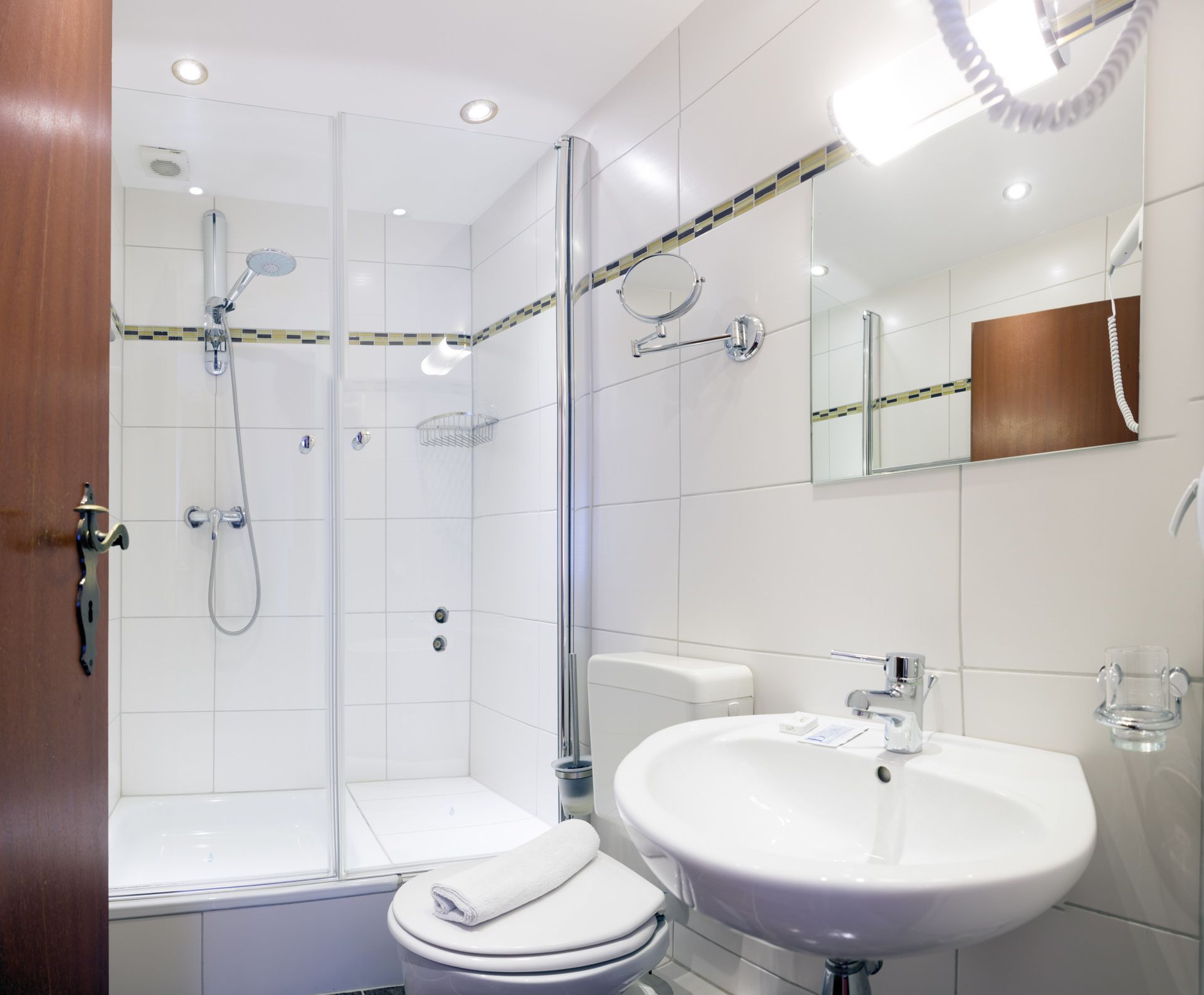 A modern bathroom with a glass-enclosed shower, a white sink, and a toilet.