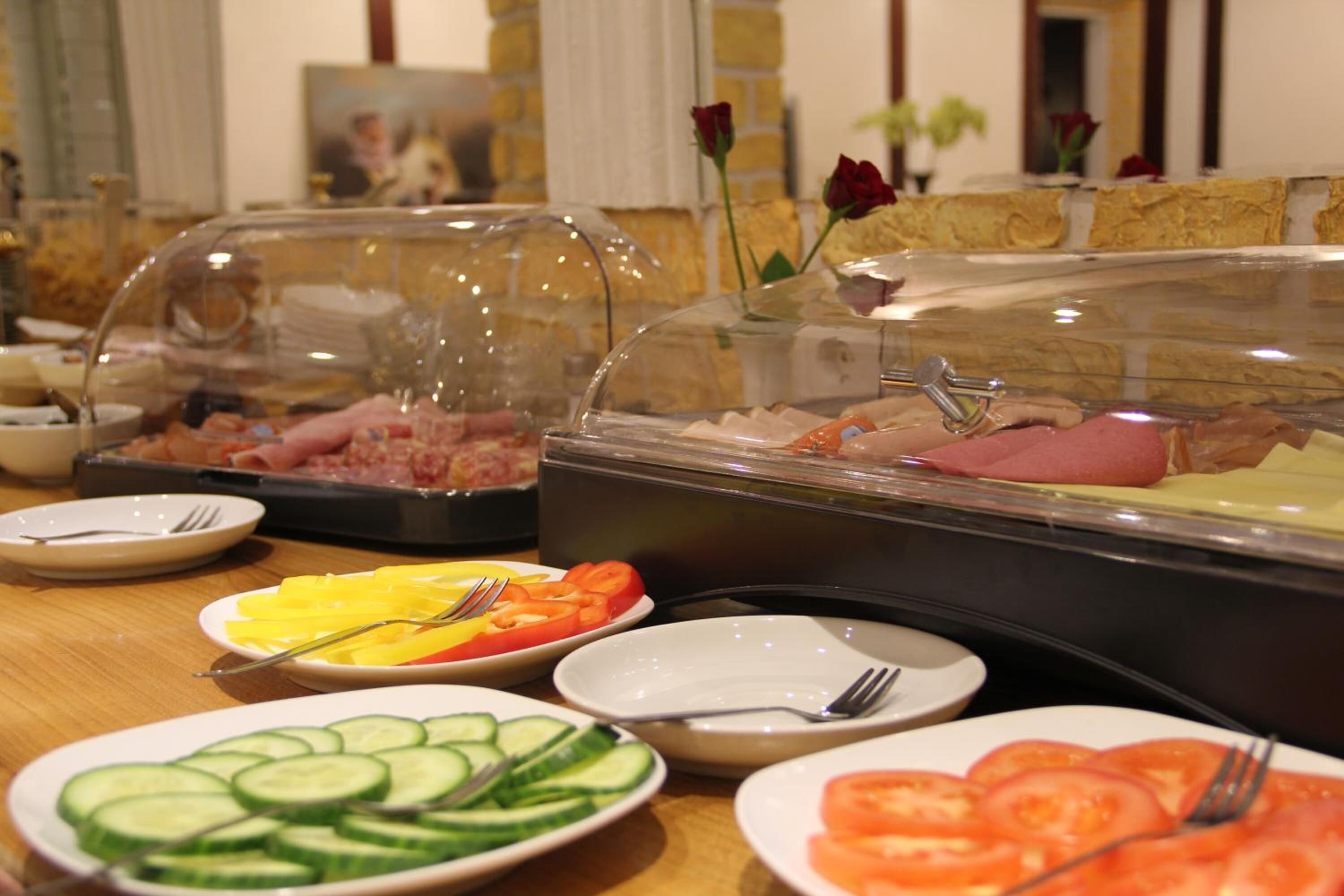 A buffet with various food items including sliced cucumbers, tomatoes, and meats.