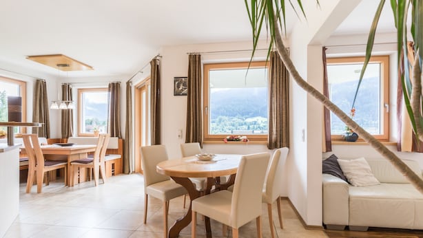 Una sala de estar moderna con comedor, ventanas amplias y vista a un paisaje nevado.