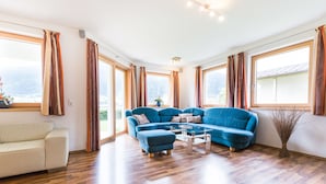 Un salón amplio con un sofá seccional azul grande, un sillón blanco y una mesa de centro.