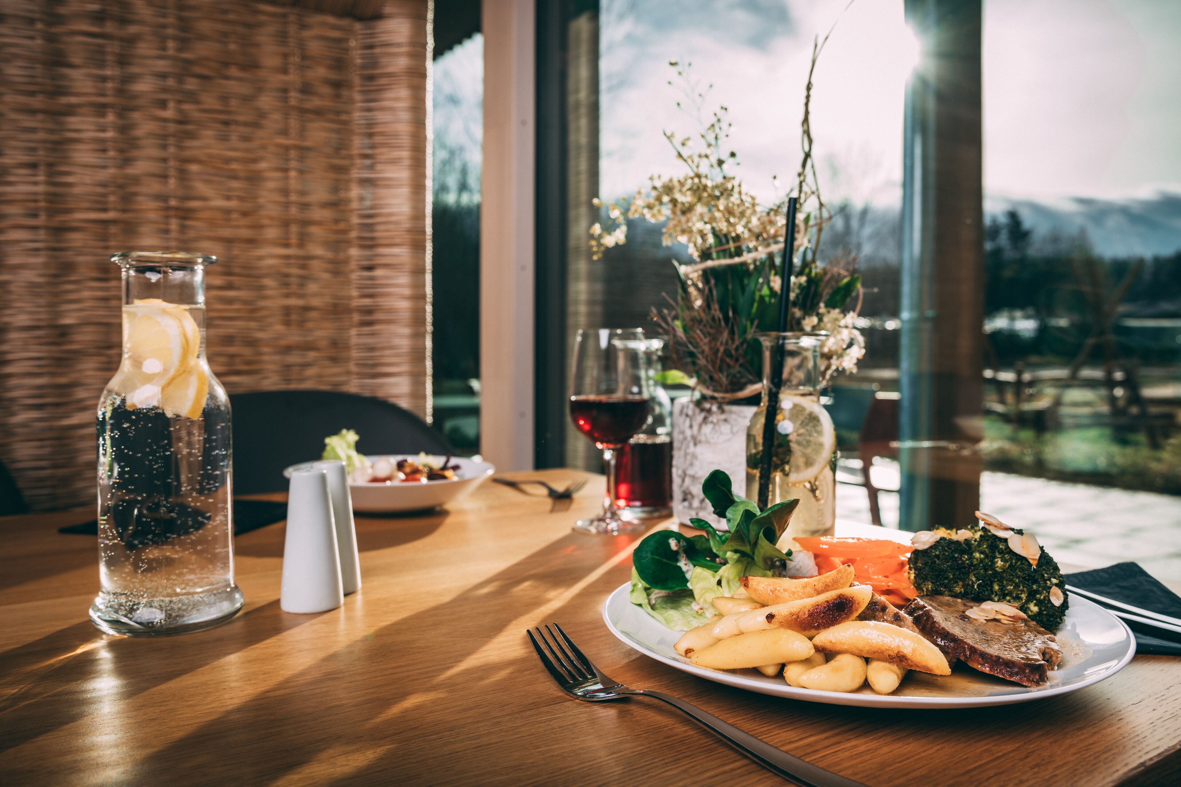 Une table à manger avec une assiette de nourriture, un verre d  ’eau et une bouteille de vin.