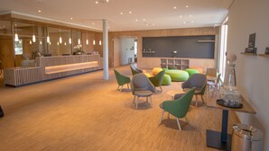 A modern reception area with a wooden reception desk, green chairs, and a blackboard wall.