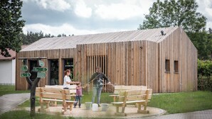 A wooden building with a sloped roof, benches, and a signpost with directional arrows.