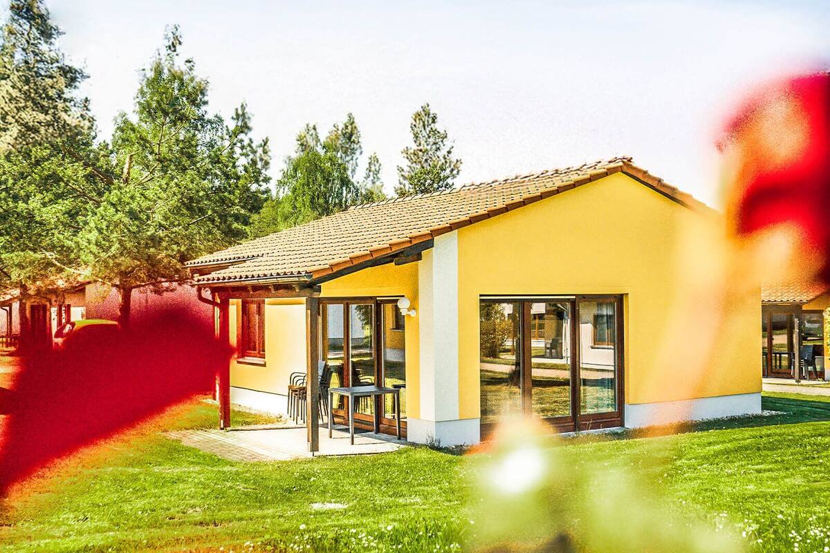 Un edificio amarillo con tejado de baldosas, amplias ventanas y un patio.