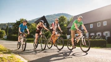 Un groupe de cyclistes sur une route asphaltée, avec un bâtiment et des arbres en arrière-plan.