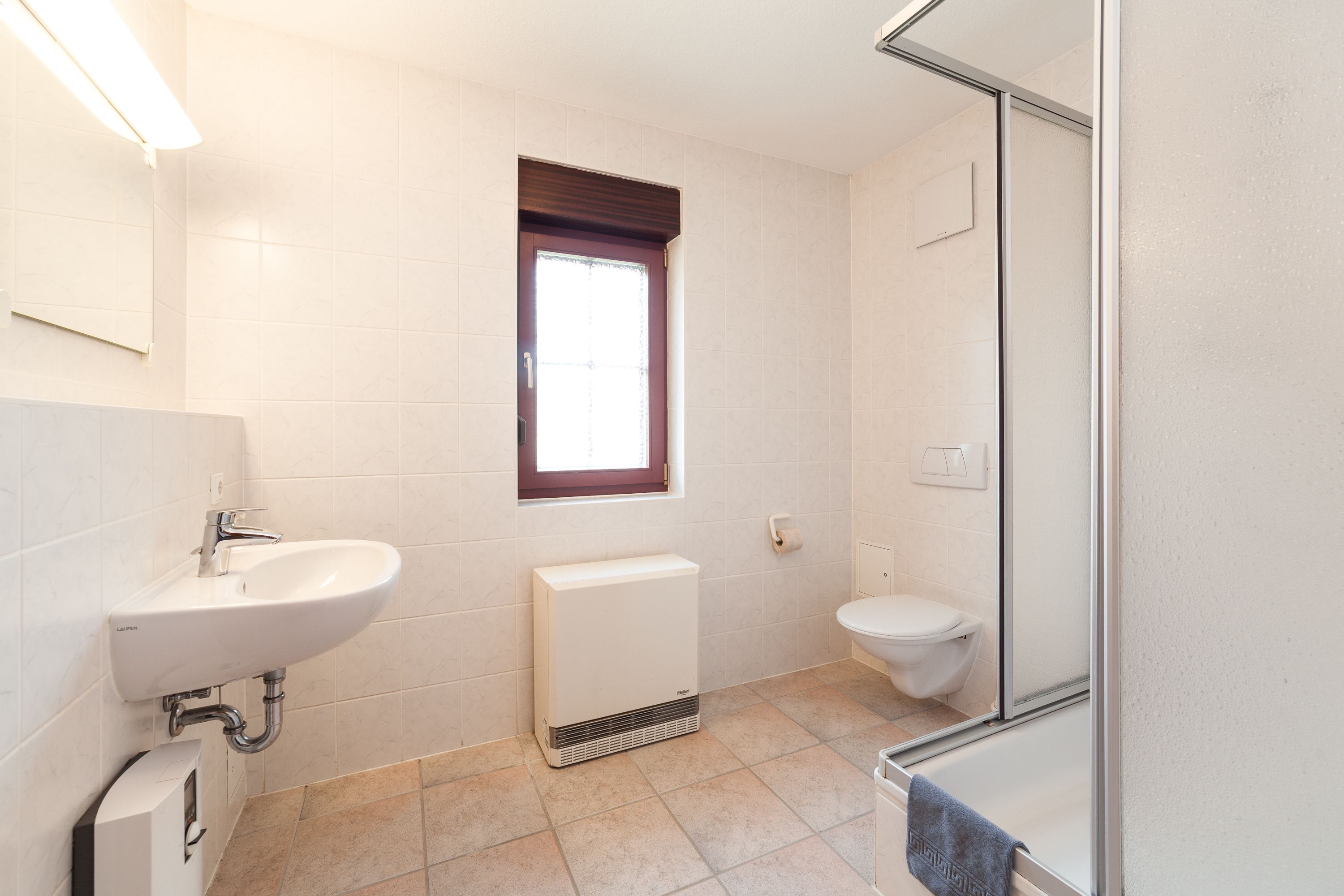 Een badkamer met een wastafel, toilet en een raam.