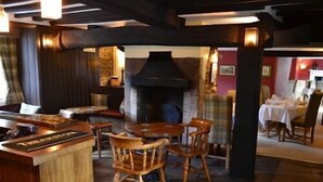A cozy restaurant with wooden furniture, a stone fireplace, and a bar area. - The Stapylton Arms (York)