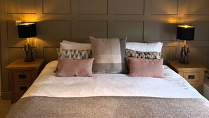 A neatly made bed with a grey blanket, two bedside tables with lamps, and a wooden ceiling beam. - The Stapylton Arms (York)