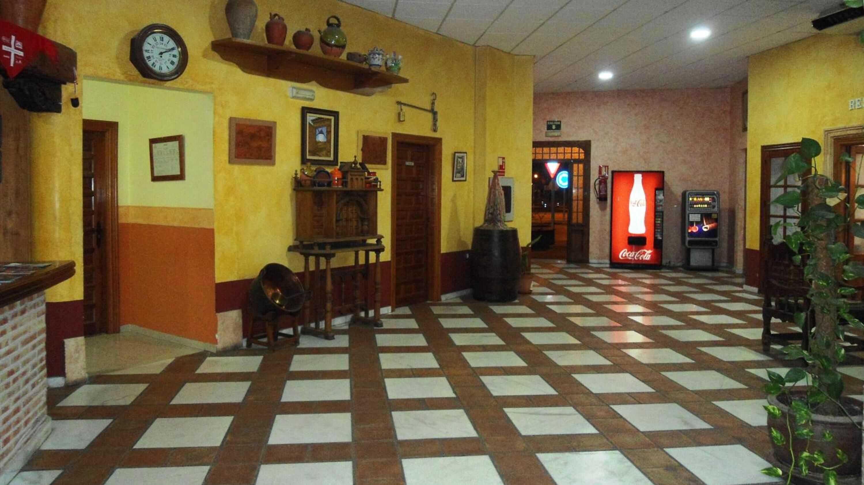 Un vestíbulo con piso a cuadros, una máquina expendedora de Coca-Cola y un reloj en la pared.