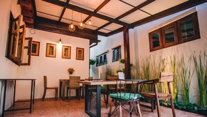 A cozy dining area with a brick floor, wooden furniture, and a ceiling with exposed beams. - Heun At Fahham (Chiang Mai)