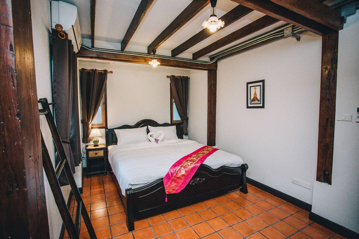 A traditional room with a bed, a nightstand, a lamp, and a picture on the wall.