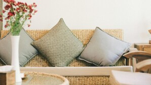 A room with a woven sofa, a vase with flowers, and a wall-mounted artwork. - Heun At Fahham (Chiang Mai)