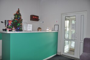 A reception area with a Christmas tree, a clock, and a sign with a message. - Z Hostel (Kyiv)