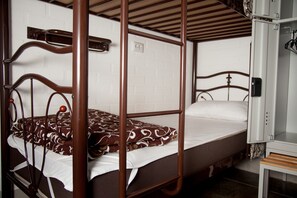 A bunk bed with a patterned blanket, a wooden headboard, and a white wall with a power outlet. - Z Hostel (Kyiv)