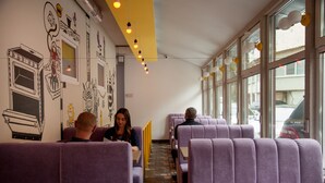 A restaurant with purple booths, a tiled floor, and a mural on the wall. - Z Hostel (Kyiv)