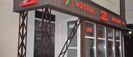 A hostel with a prominent 'HOSTEL' sign and a neon 'OPEN' sign.