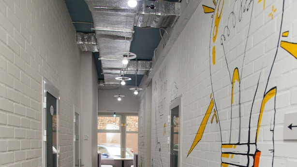 A corridor with white brick walls, a polished concrete floor, and graffiti art. - Z Hostel (Kyiv)