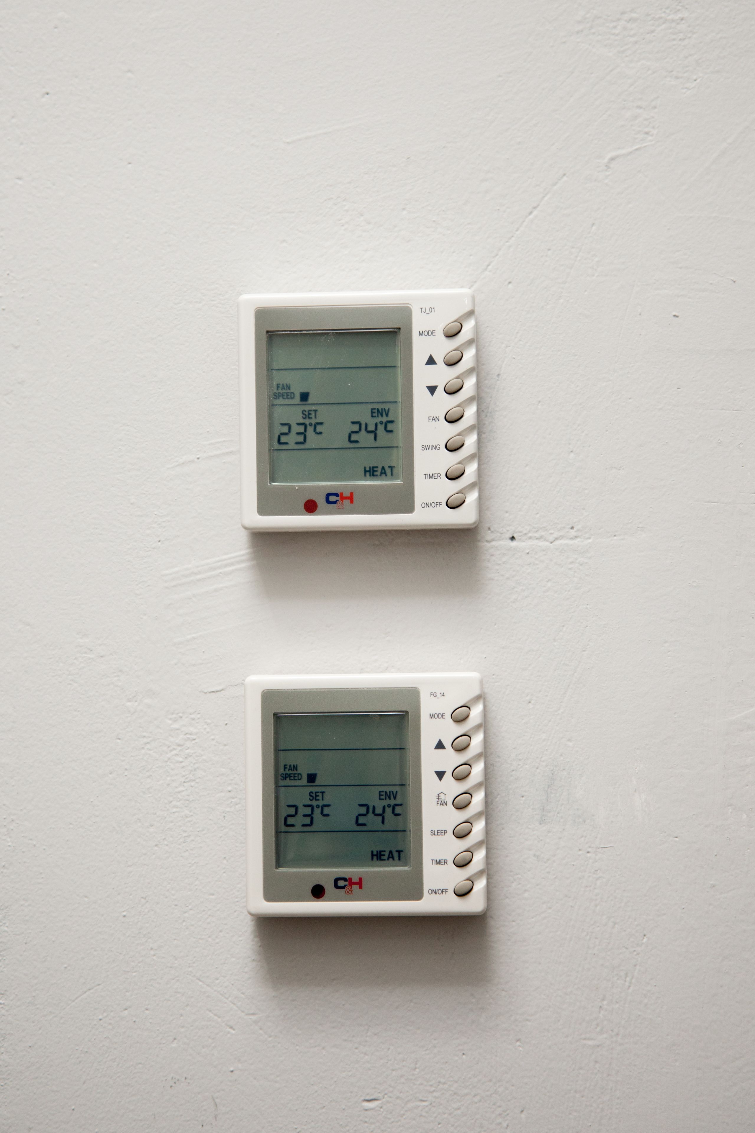 Two wall-mounted thermostats displaying temperature settings.