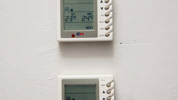 Two wall-mounted thermostats displaying temperature settings.